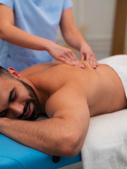 Frau liegt auf einer Liege. Die Heilpraktikerin führt Chiropraktik durch.