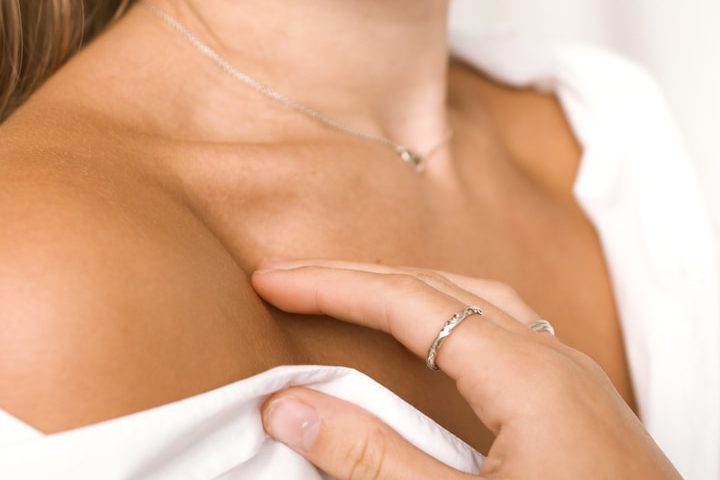 Nahaufnahme einer Person. Sie berührt die Haut an der Schulter.