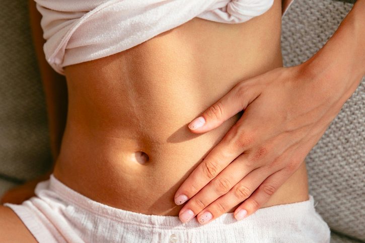 Eine Hand liegt auf dem Bauch.