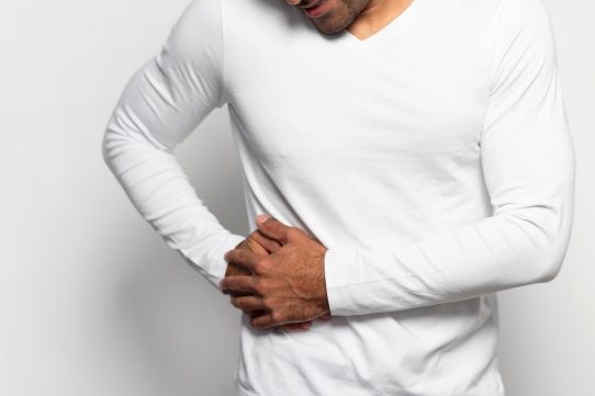 Mann fasst sich mit einer Hand in die Seite.