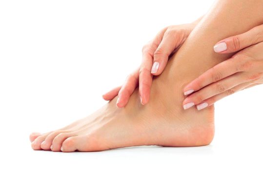 Hände halten sanft den Knöchel eines Fußes.