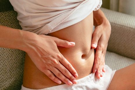 Eine Person mit freiem Bauchbereich, die ihre Hände auf den Bauch legt.