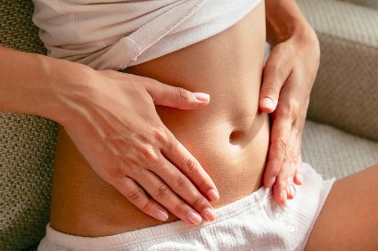 Hände berühren sanft den Bauch bei Reizdarm.