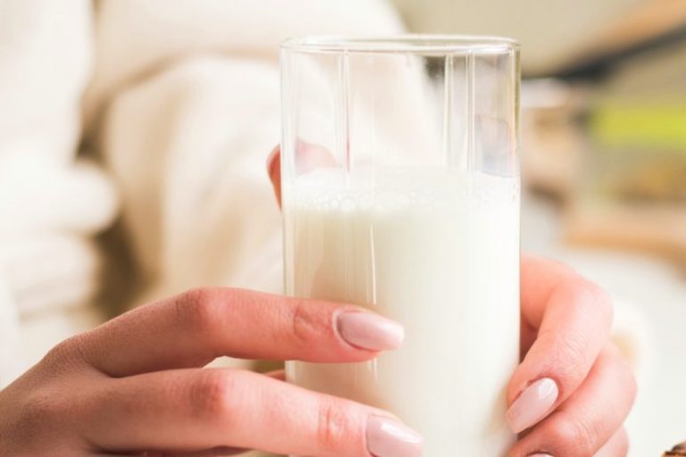 Hände halten ein Glas Milch.