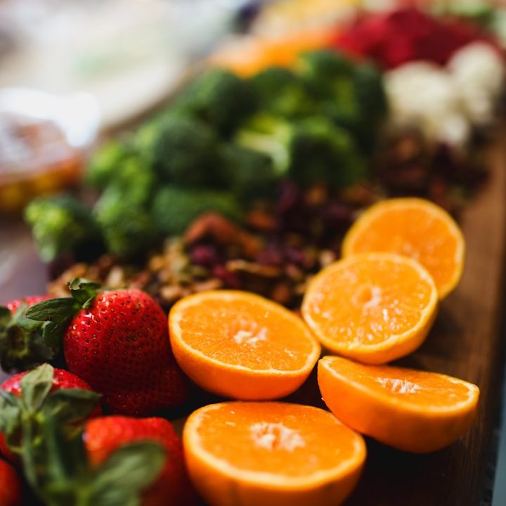 Bunte Auswahl an frischem Obst und Gemüse, darunter Orangen, Erdbeeren und Brokkoli.