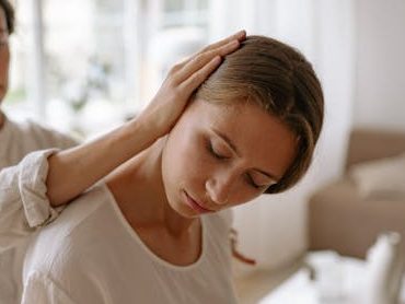 Eine Frau erhält eine sanfte Chiropraktik Anwendung am Nacken in einem hellen, modernen Raum.