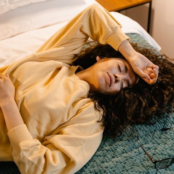 Eine Frau liegt mit Kopfschmerzen im Bett.