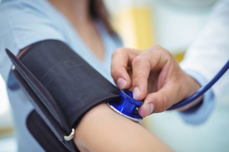 Eine Frau erhält eine Blutdruckmessung mit einem Blutdruckmessgerät am Arm.