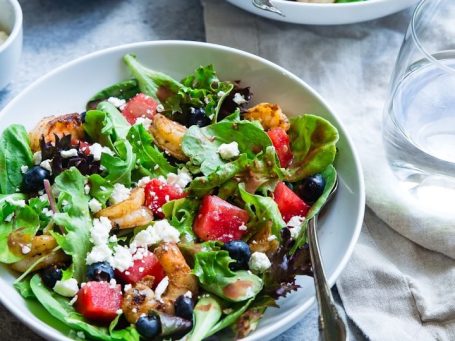 Eine Schüssel mit gemischtem Salat, Wassermelonenstücken, Feta und Beeren.